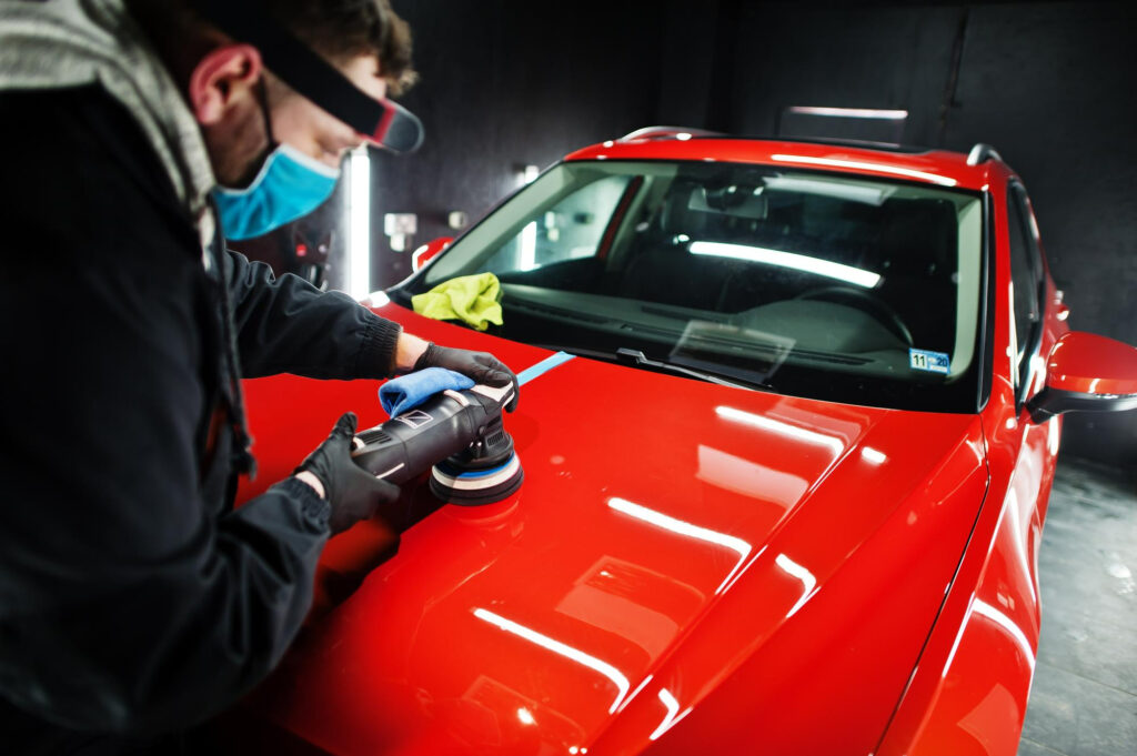 Mann poliert rotes Auto.